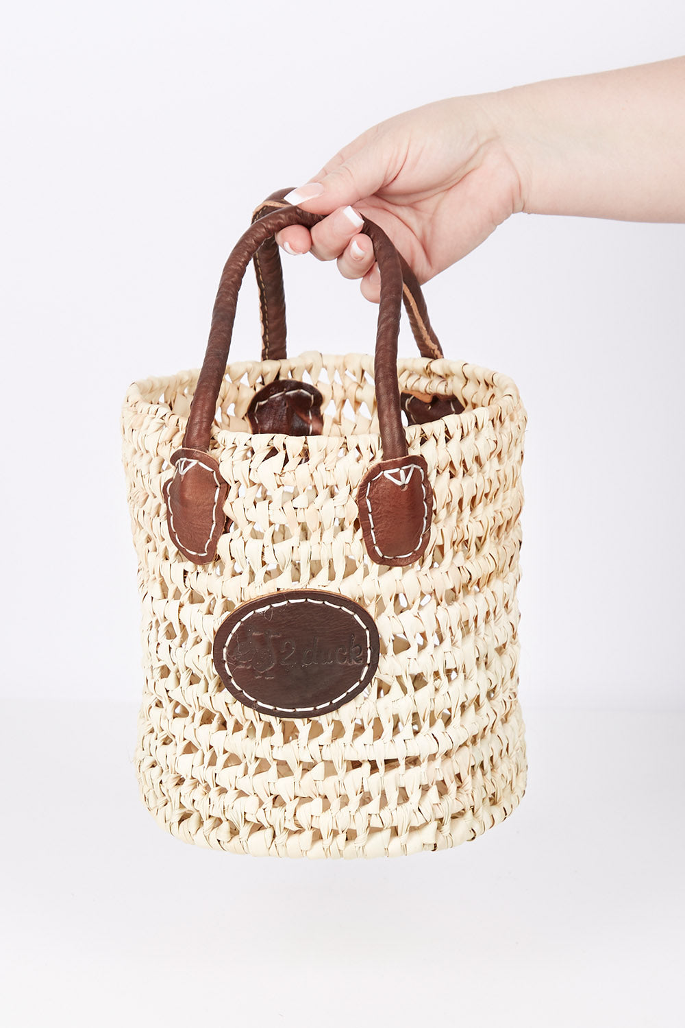 A model wearing size OneSize of the Small Round Open Weave Handle Basket in colour Natural, from the front, showing the whole outfit