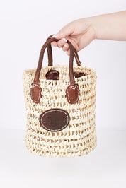 A model wearing size OneSize of the Small Round Open Weave Handle Basket in colour Natural, from the front, showing the whole outfit