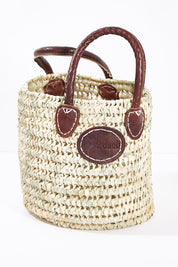 A model wearing size OneSize of the Small Round Open Weave Handle Basket in colour Natural, from the front, showing the whole outfit