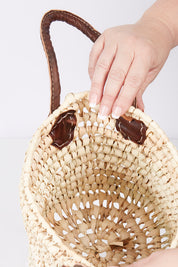 A model wearing size OneSize of the Small Round Open Weave Handle Basket in colour Natural, from the front, showing the whole outfit