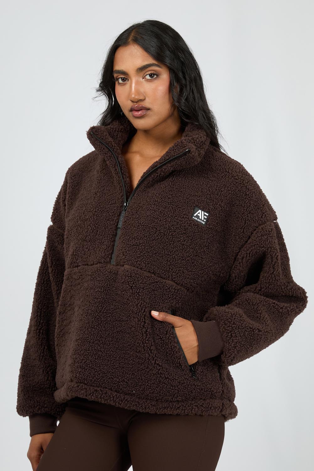 A model wearing the Amara Quarter Zip Teddy in colour Brown, from the front, cropped image