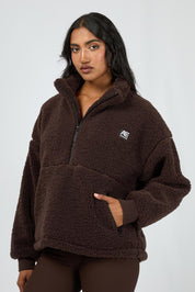 A model wearing the Amara Quarter Zip Teddy in colour Brown, from the front, cropped image