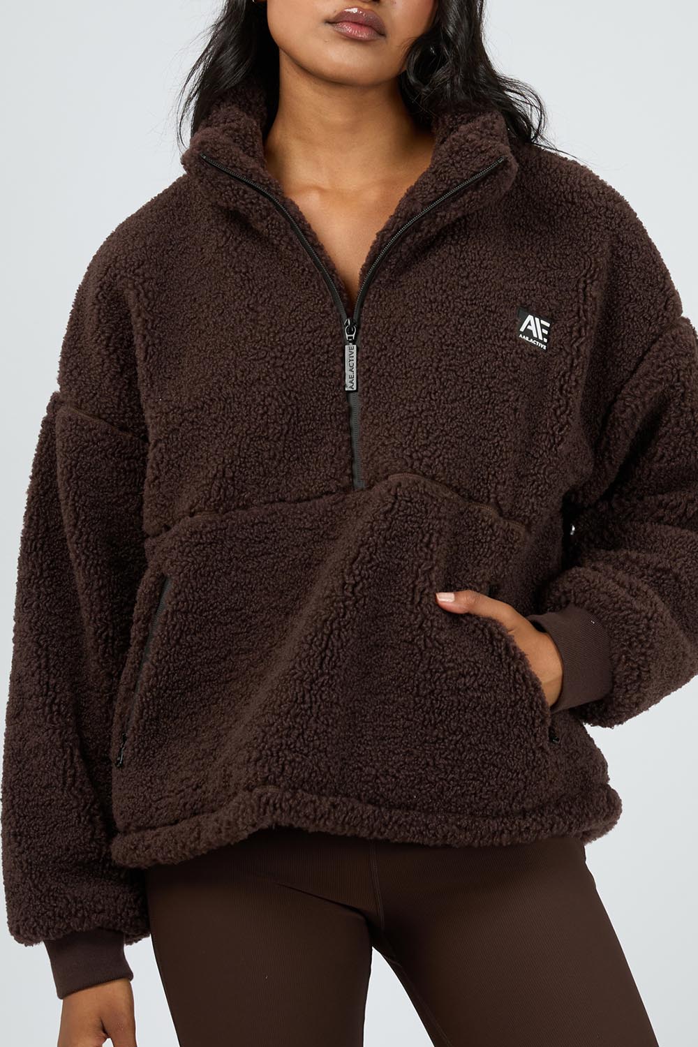 A model wearing the Amara Quarter Zip Teddy in colour Brown, from the front, cropped image