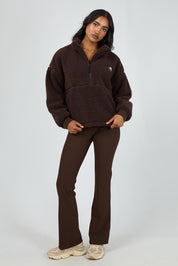 A model wearing the Amara Quarter Zip Teddy in colour Brown, from the front, showing the whole outfit