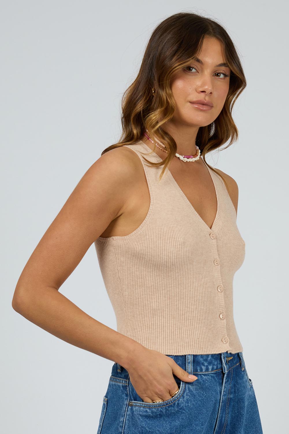 A model wearing the Henley Knit Vest in colour Oat, from the front, cropped image