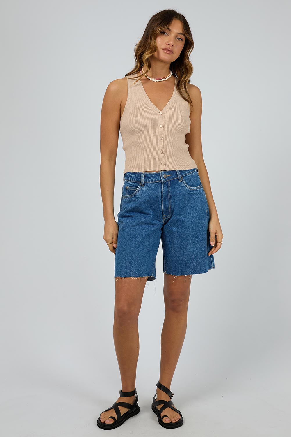 A model wearing the Henley Knit Vest in colour Oat, from the front, showing the whole outfit