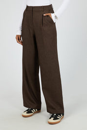 A model wearing the Romy Wide Leg Pant in colour Brown, from the front, cropped image