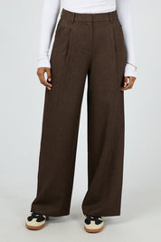 A model wearing the Romy Wide Leg Pant in colour Brown, from the front, cropped image