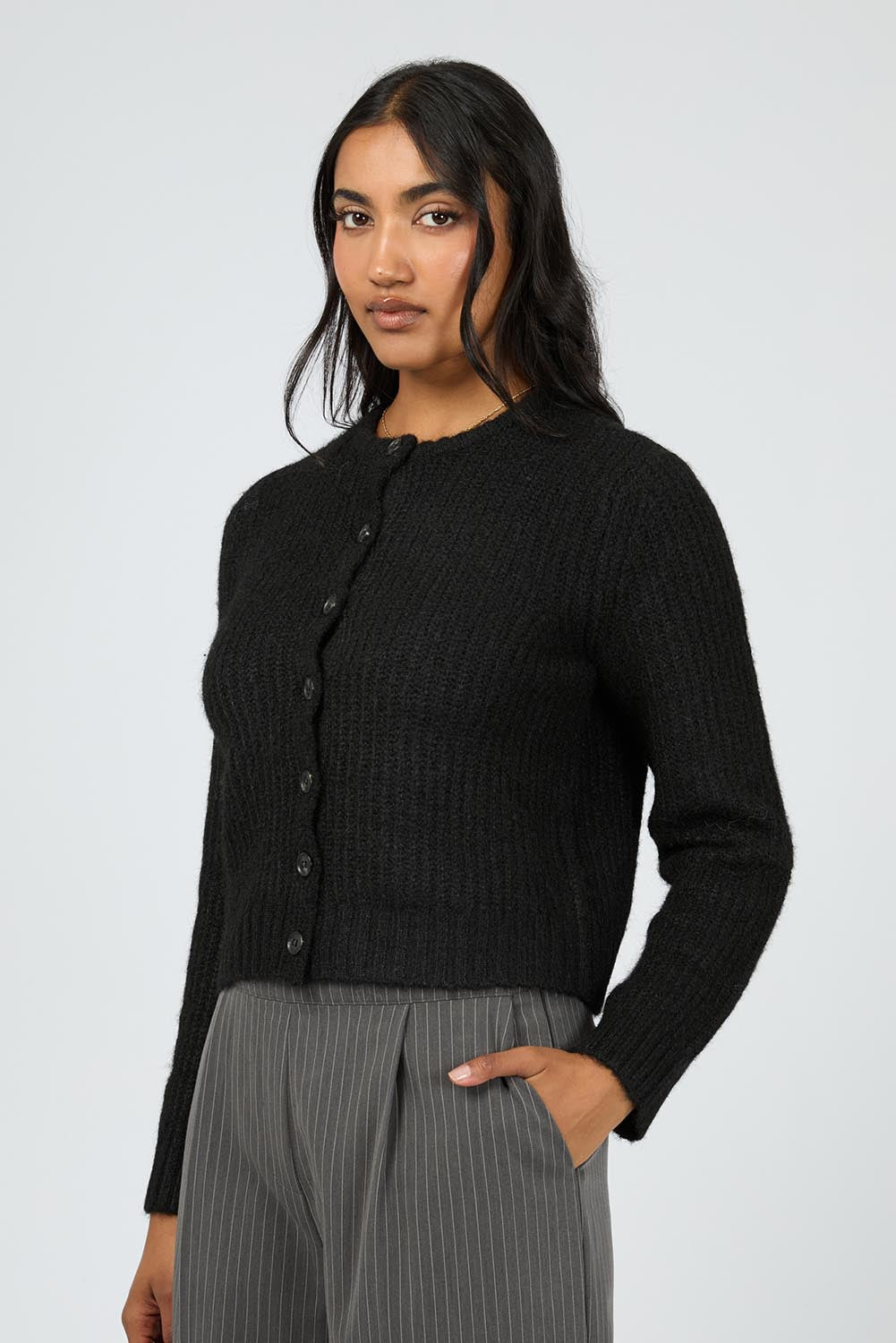 A model wearing the Aya Cardigan in colour Black (Black), from the front, cropped image