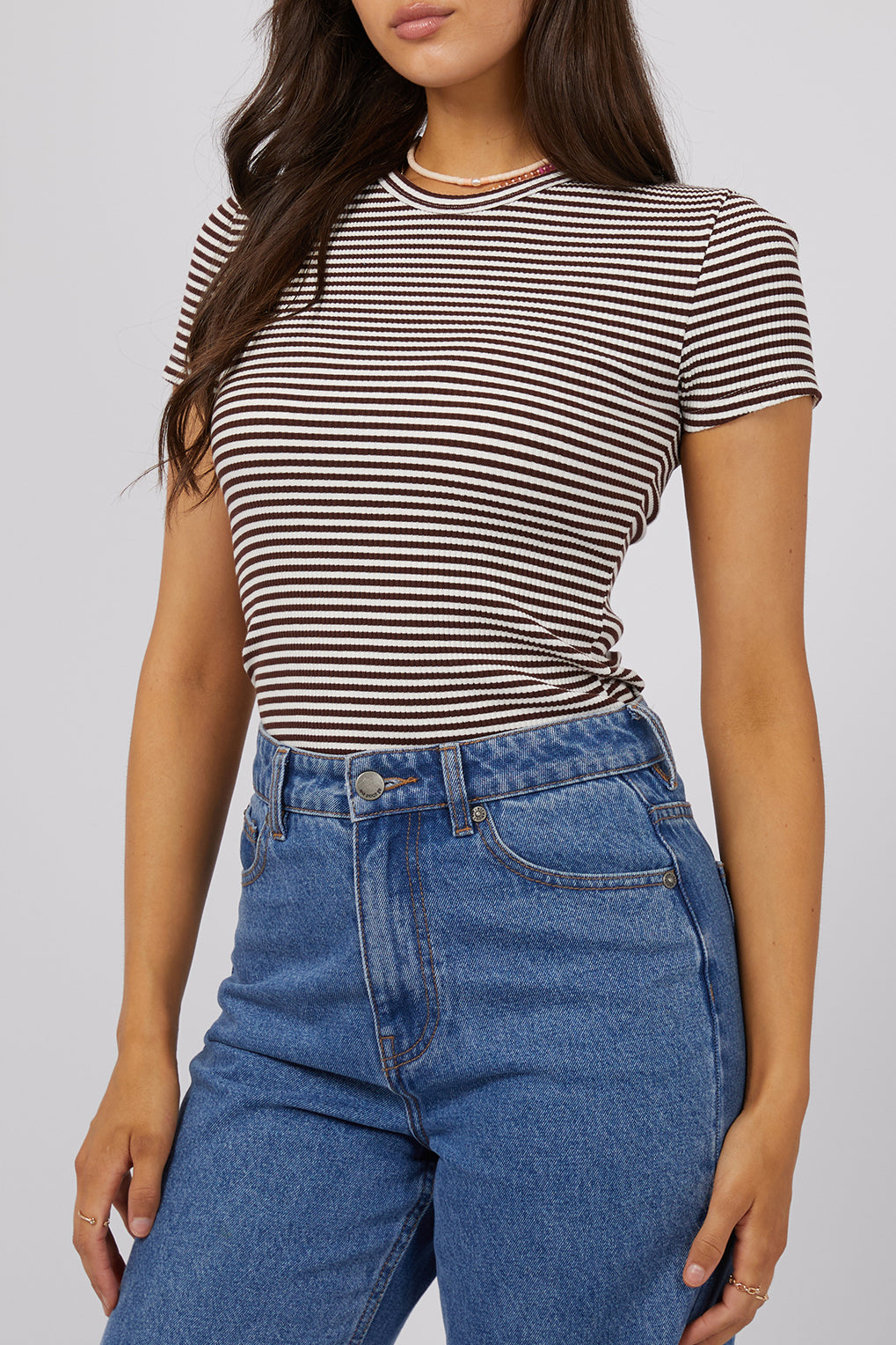 A model wearing the Eve Rib Stripe Tee in colour Brown, from the front, cropped image