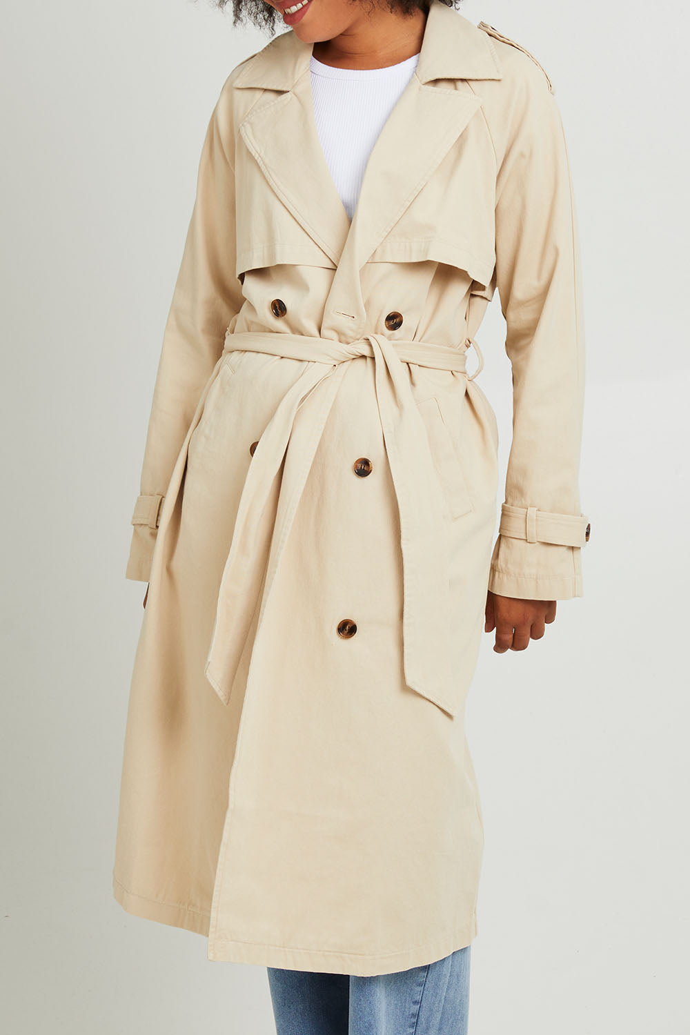 Model Olivia wearing size 10 of the Eve Trench Coat in colour Tan, from the front, cropped image