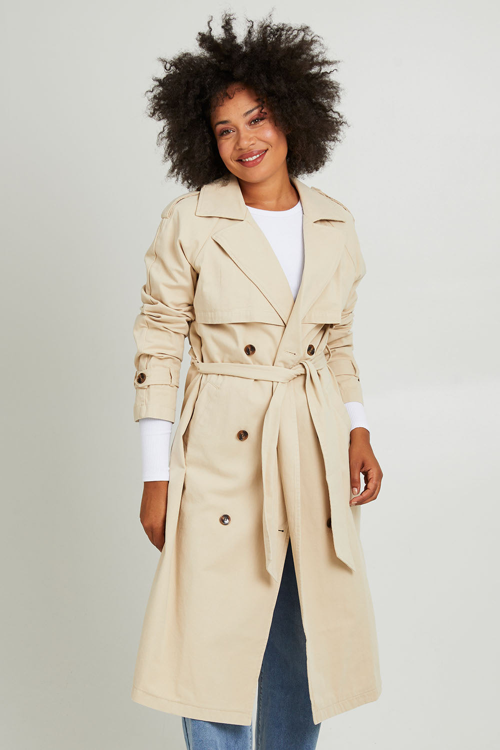 Model Olivia wearing size 10 of the Eve Trench Coat in colour Tan, from the front, cropped image