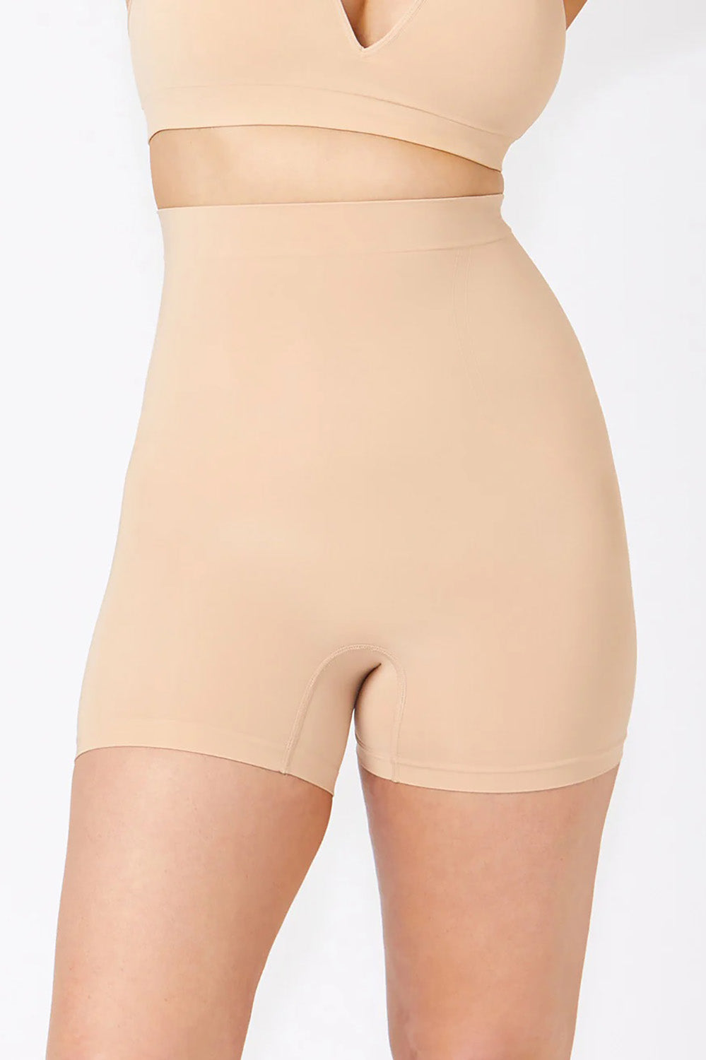 A model wearing the Powerlite High Waisted Short in colour Beige, from the front, cropped image