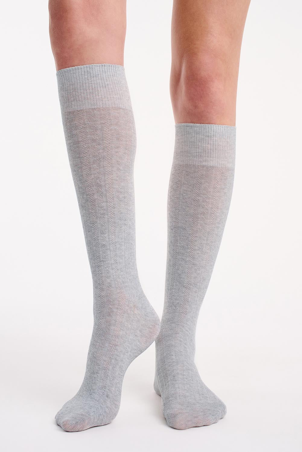 A model wearing the Organic Cotton Cable Knit Knee High Socks in colour Greymarle (Grey), from the front, cropped image