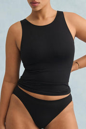 A model wearing the Reversible Shelf Bra Tank in colour Black (Black), from the front, cropped image