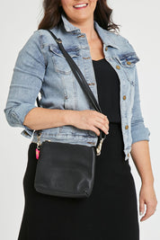 Model Tahlecia wearing size OneSize of the Alexis Leather Crossbody in colour Black (Black), from the front, cropped image