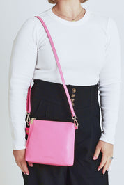 Model Steph wearing size OneSize of the Alexis Leather Crossbody in colour Blossom (Pink), from the front, cropped image