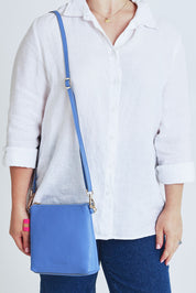 Model Steph wearing size OneSize of the Alexis Leather Crossbody in colour Cornflower (Blue), from the front, cropped image