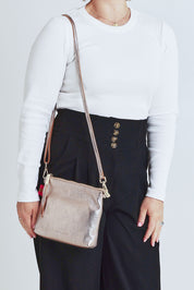 Model Steph wearing size OneSize of the Alexis Leather Crossbody in colour Gold (Metallics), from the front, cropped image