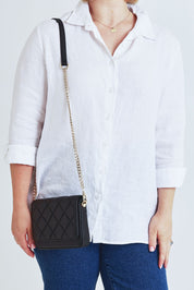 Model Steph wearing the Sarah Leather Quilted Crossbody in colour Black (Black), from the front, cropped image