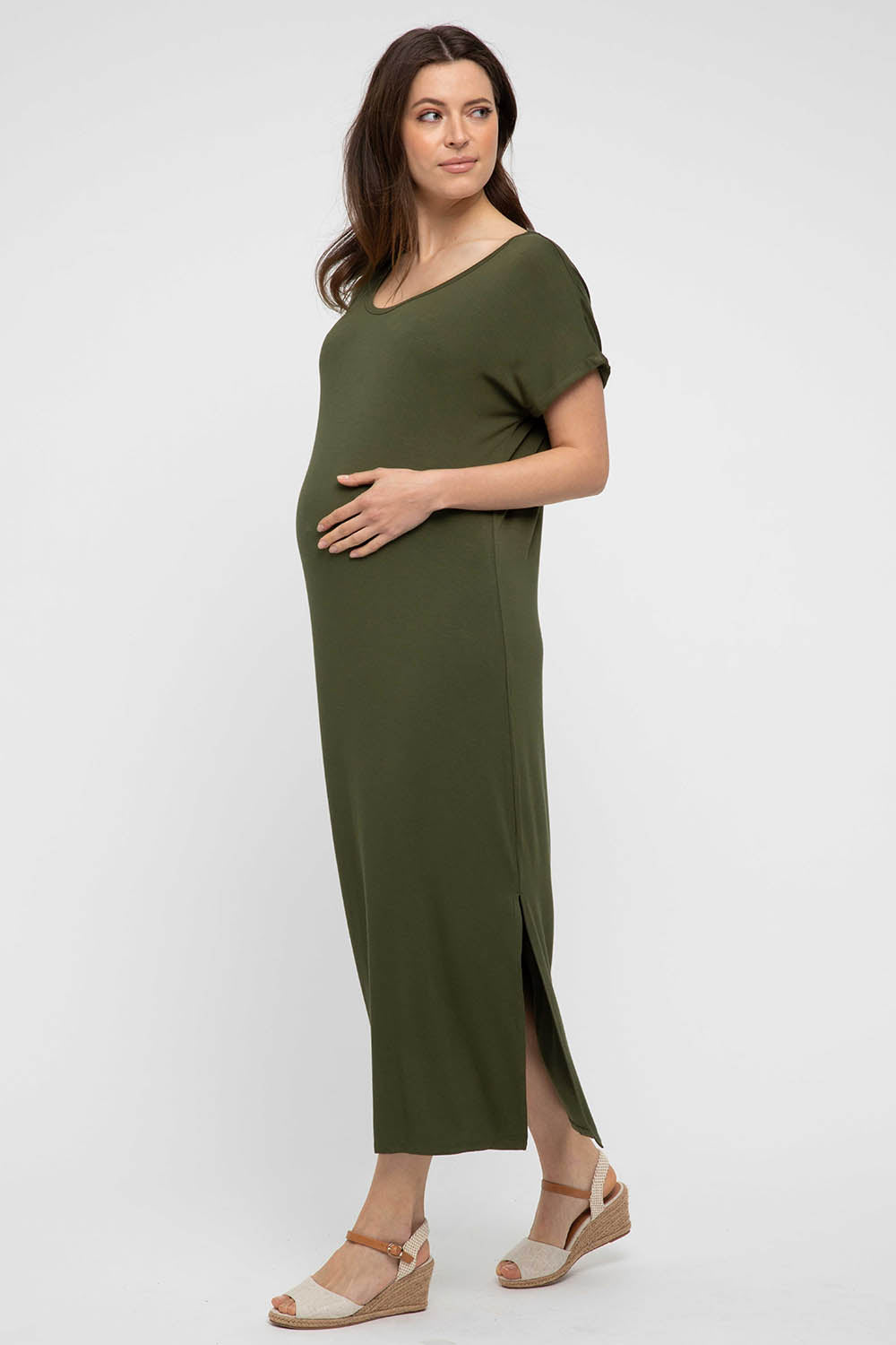 A model wearing the Elsie Dress in colour Darkolive (Green), from the front, showing the whole outfit
