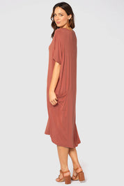 A model wearing the Samara Dress in colour Cedarwood, from the back