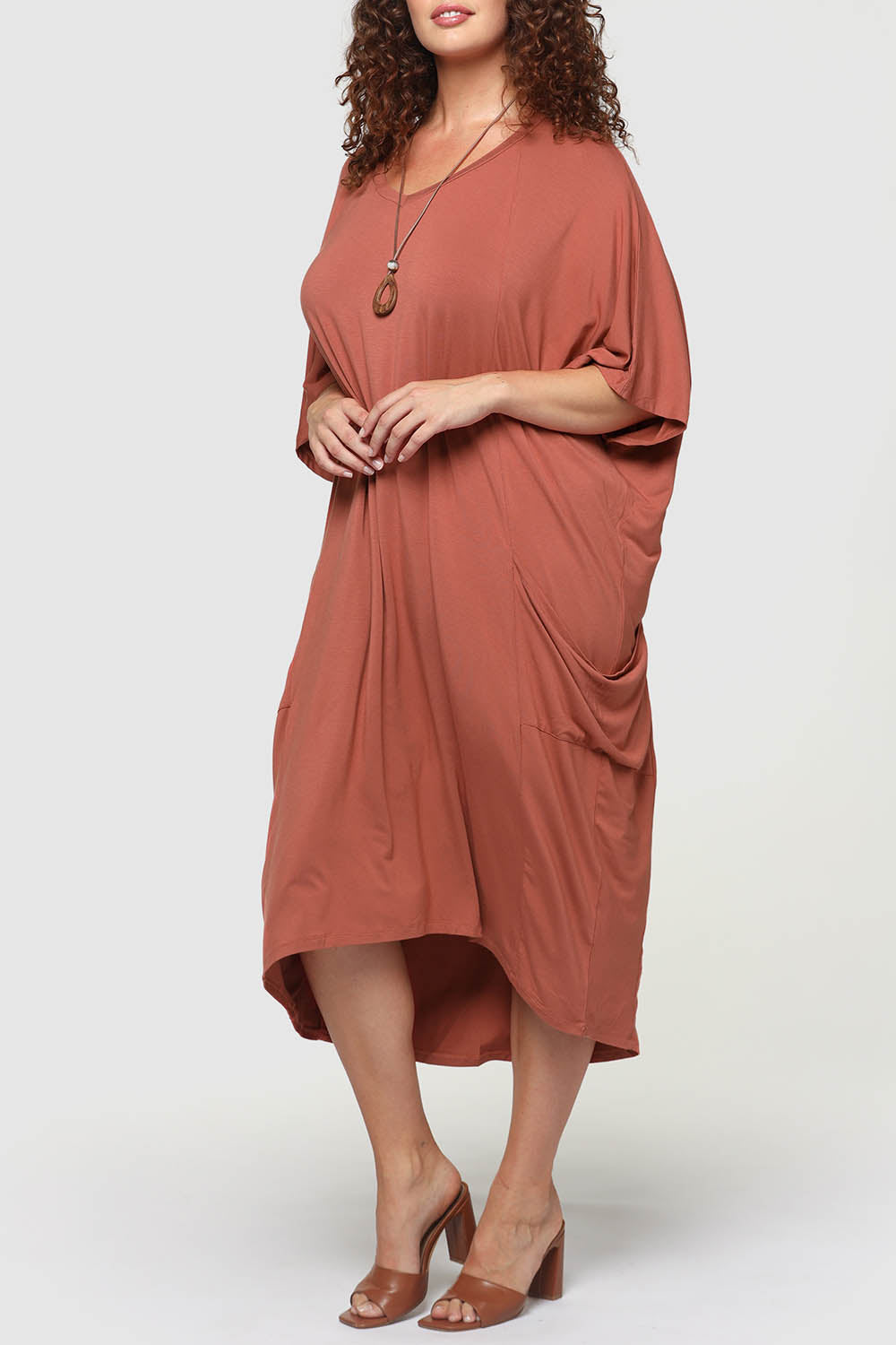 A model wearing the Samara Dress in colour Cedarwood, from the front, cropped image