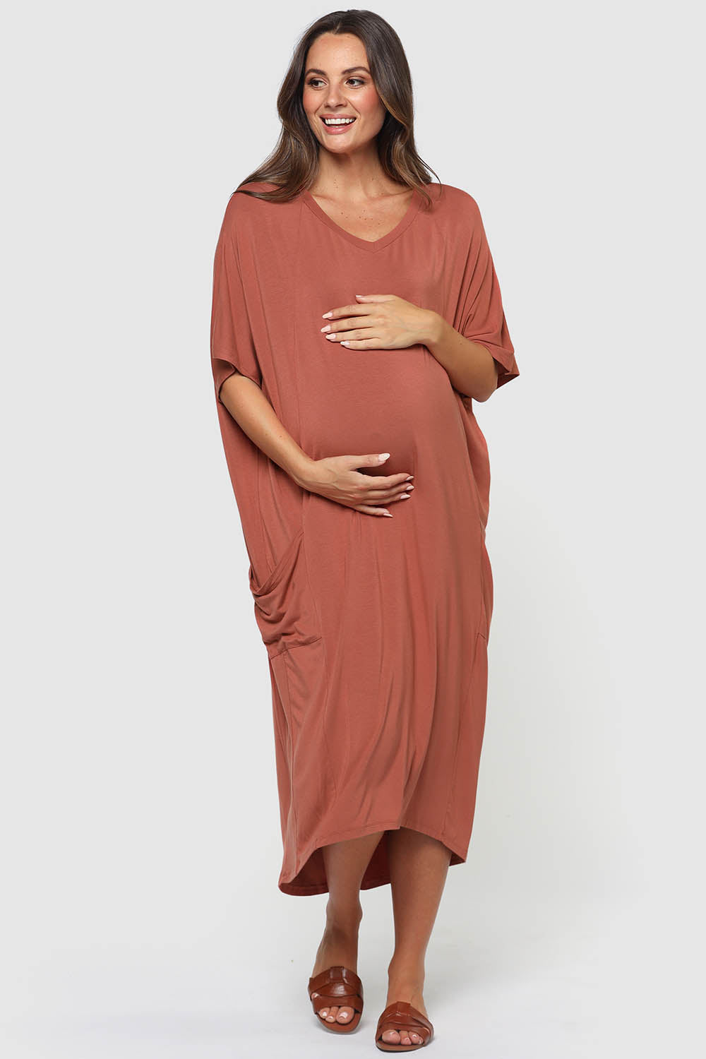 A model wearing the Samara Dress in colour Cedarwood, from the front, showing the whole outfit