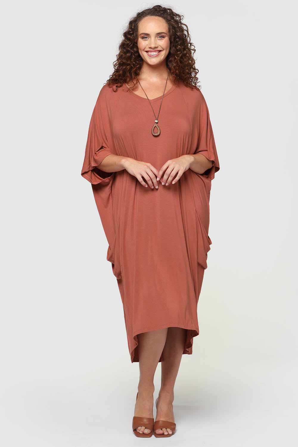 A model wearing the Samara Dress in colour Cedarwood, from the front, showing the whole outfit