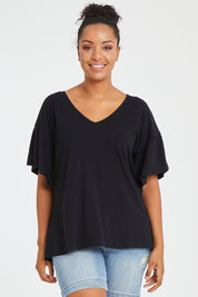 Model Noli wearing size 14 of the Alessi Frill Top in colour Black (Black), from the front, cropped image