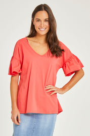 Model Elhana wearing size 10 of the Alessi Frill Top in colour Strawberry (Pink), from the front, cropped image