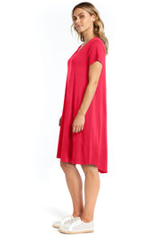 A model wearing the Brooke Dress in colour Rosered (Red), from the front, showing the whole outfit