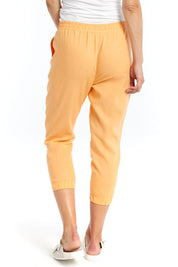 A model wearing the Lennon Pant in colour Mango, from the back