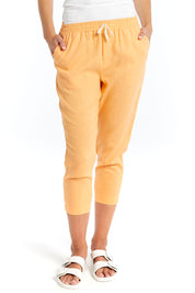 A model wearing the Lennon Pant in colour Mango, from the front, cropped image
