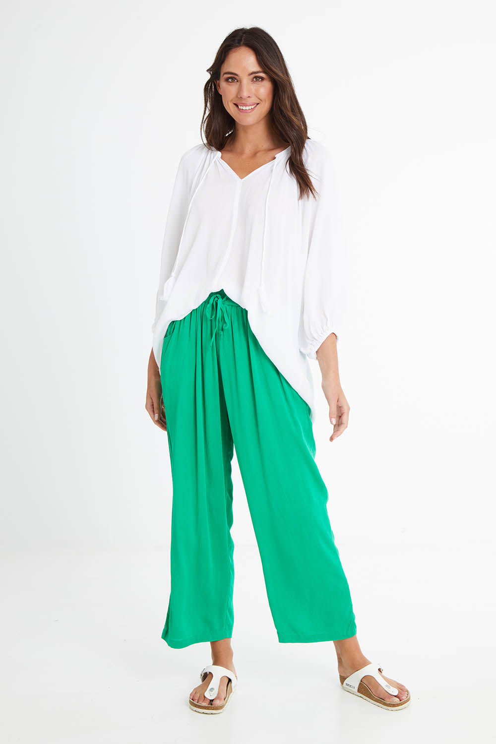 Model Madeline wearing size 10 of the Rani Pants in colour Green (Green), from the front, showing the whole outfit