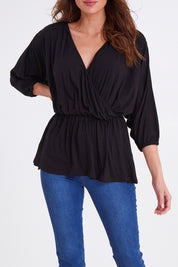 Model Madeline wearing size 10 of the Bayeaux Wrap Top in colour Black (Black), from the front, cropped image