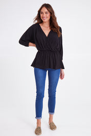 Model Madeline wearing size 10 of the Bayeaux Wrap Top in colour Black (Black), from the front, showing the whole outfit