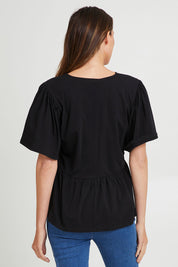 Model Madeline wearing size 10 of the Celia Tee in colour Black (Black), from the back