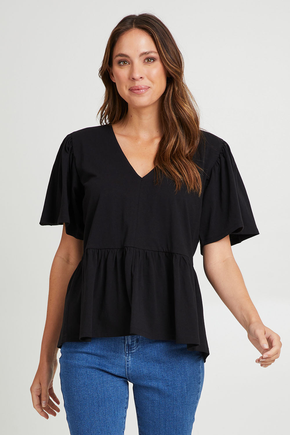 Model Madeline wearing size 10 of the Celia Tee in colour Black (Black), from the front, cropped image