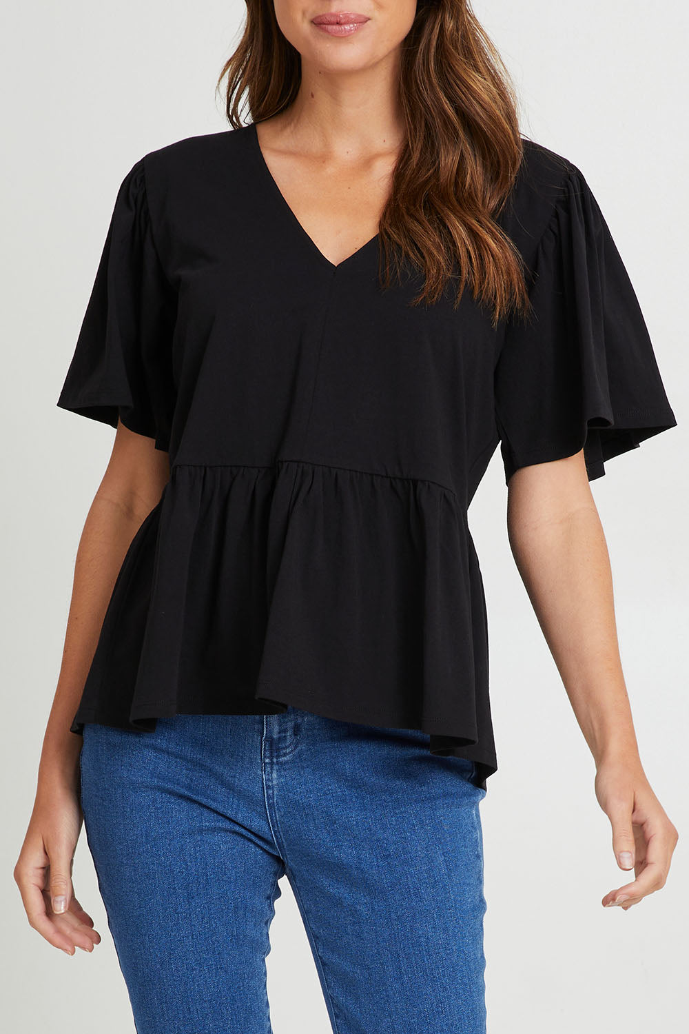 Model Madeline wearing size 10 of the Celia Tee in colour Black (Black), from the front, cropped image