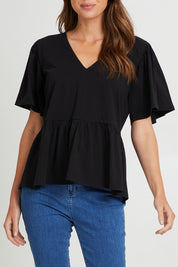 Model Madeline wearing size 10 of the Celia Tee in colour Black (Black), from the front, cropped image