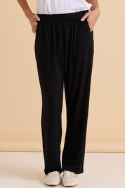 A model wearing the Ginnie Bamboo Pant in colour Black (Black), from the front, cropped image