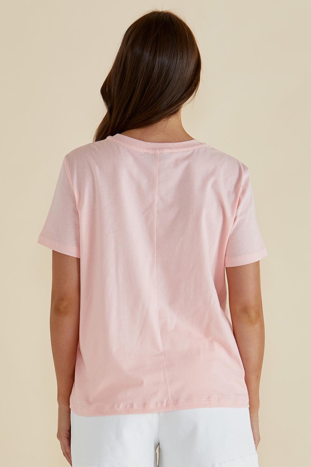A model wearing the Ellia Cotton Crew Tee in colour Santorini (Pink), from the back