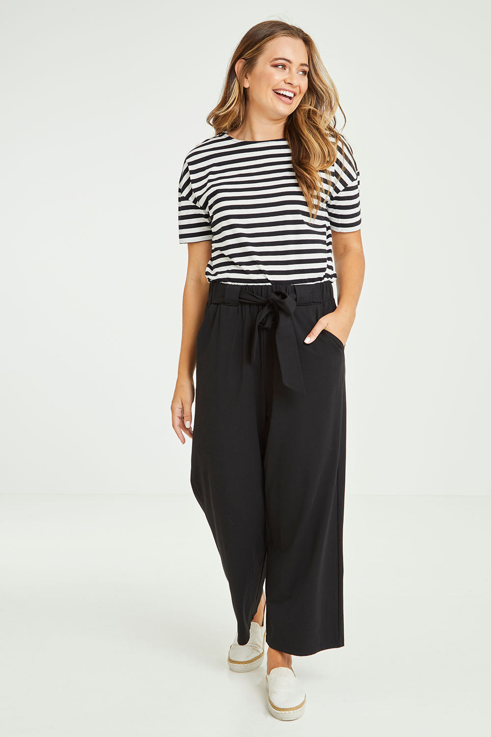 Model Tahlia wearing size 10 of the Dasha Pant in colour Black (Black), from the front, showing the whole outfit