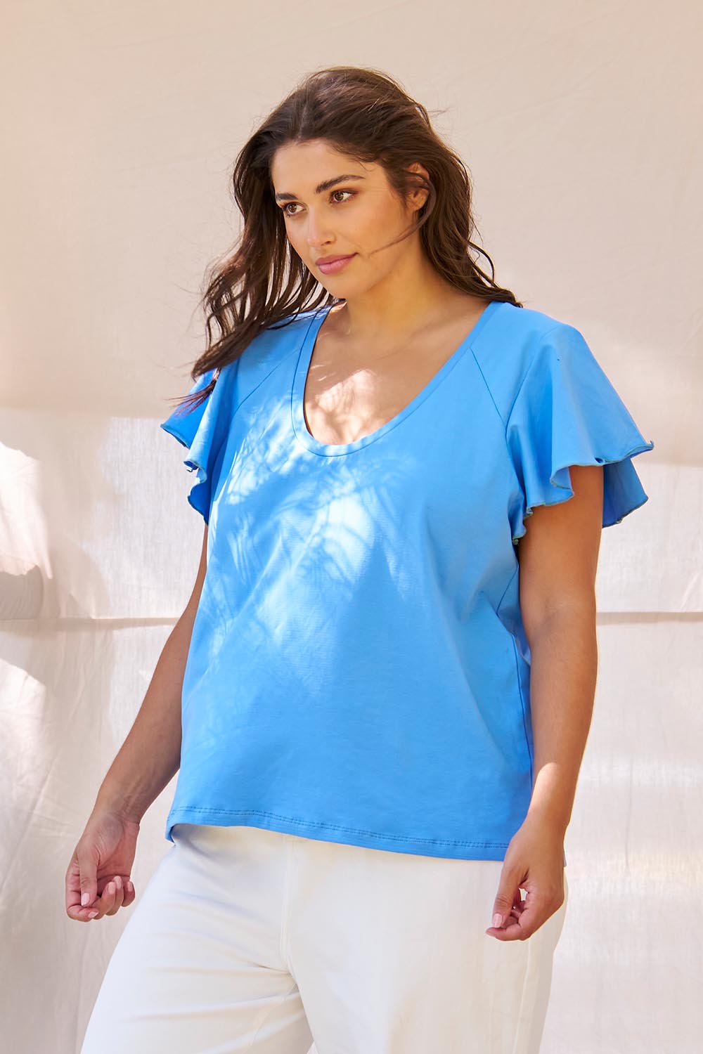 A model wearing the Magnolia Cotton Frill Sleeve Top in colour Powderblue (Blue), from the front, showing the whole outfit
