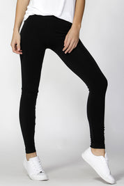 A model wearing the Christina Legging in colour Black (Black), from the front, cropped image