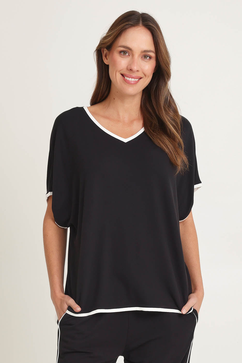 Model Madeline wearing size 10 of the Clara Tee in colour Black (Black), from the front, cropped image