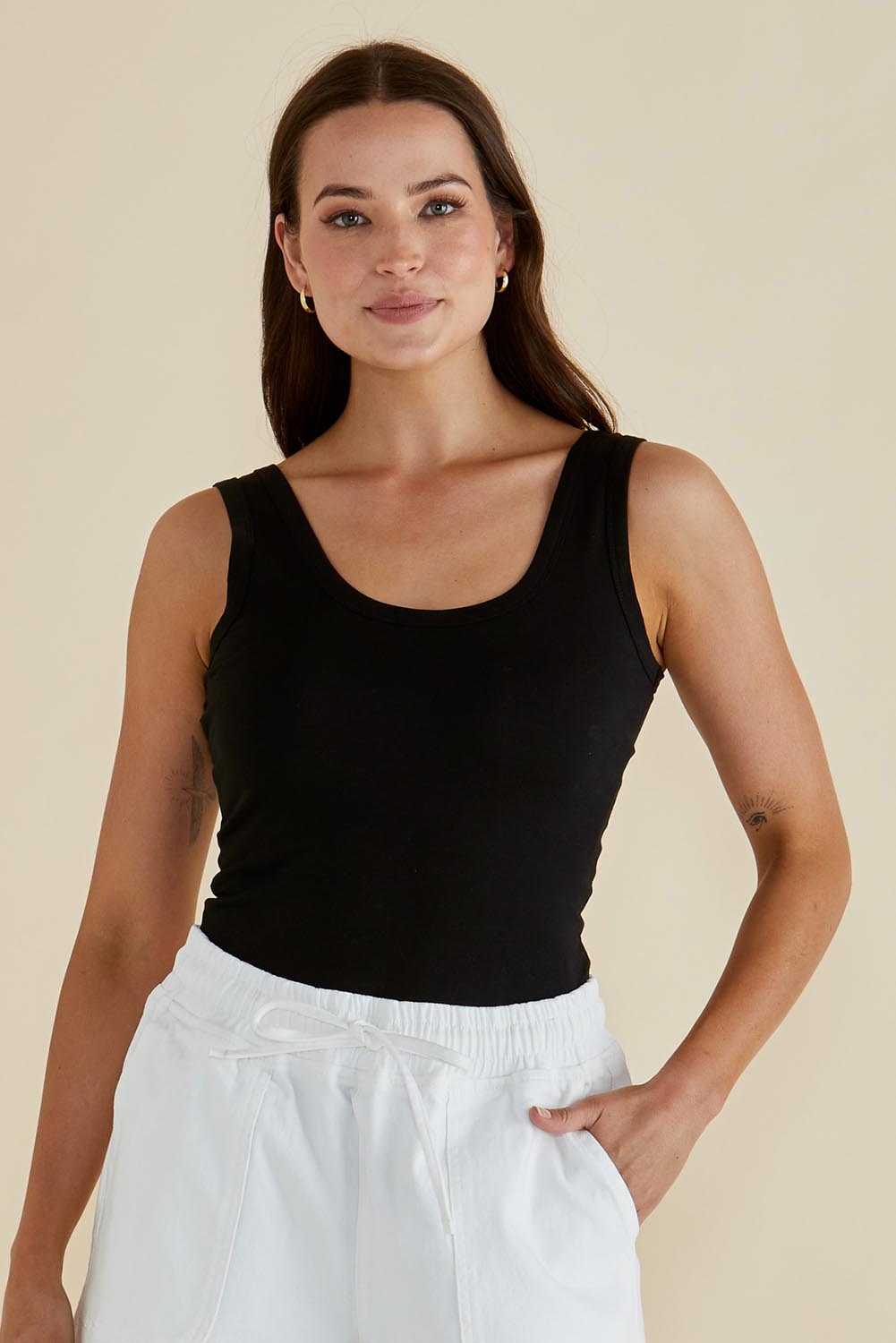 A model wearing the Emma Cotton Scoop Tank in colour Black (Black), from the front, cropped image