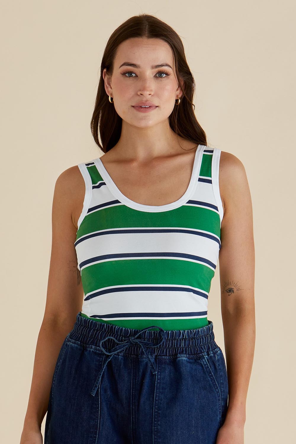A model wearing the Emma Cotton Scoop Tank in colour Green (Green), from the front, cropped image