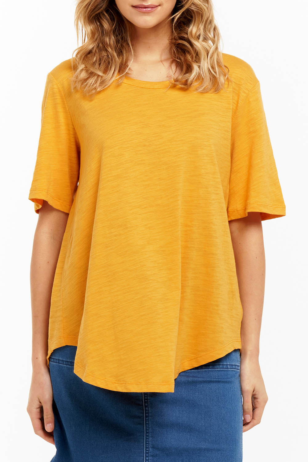 A model wearing the Ariana Tee in colour Mustard, from the front, cropped image